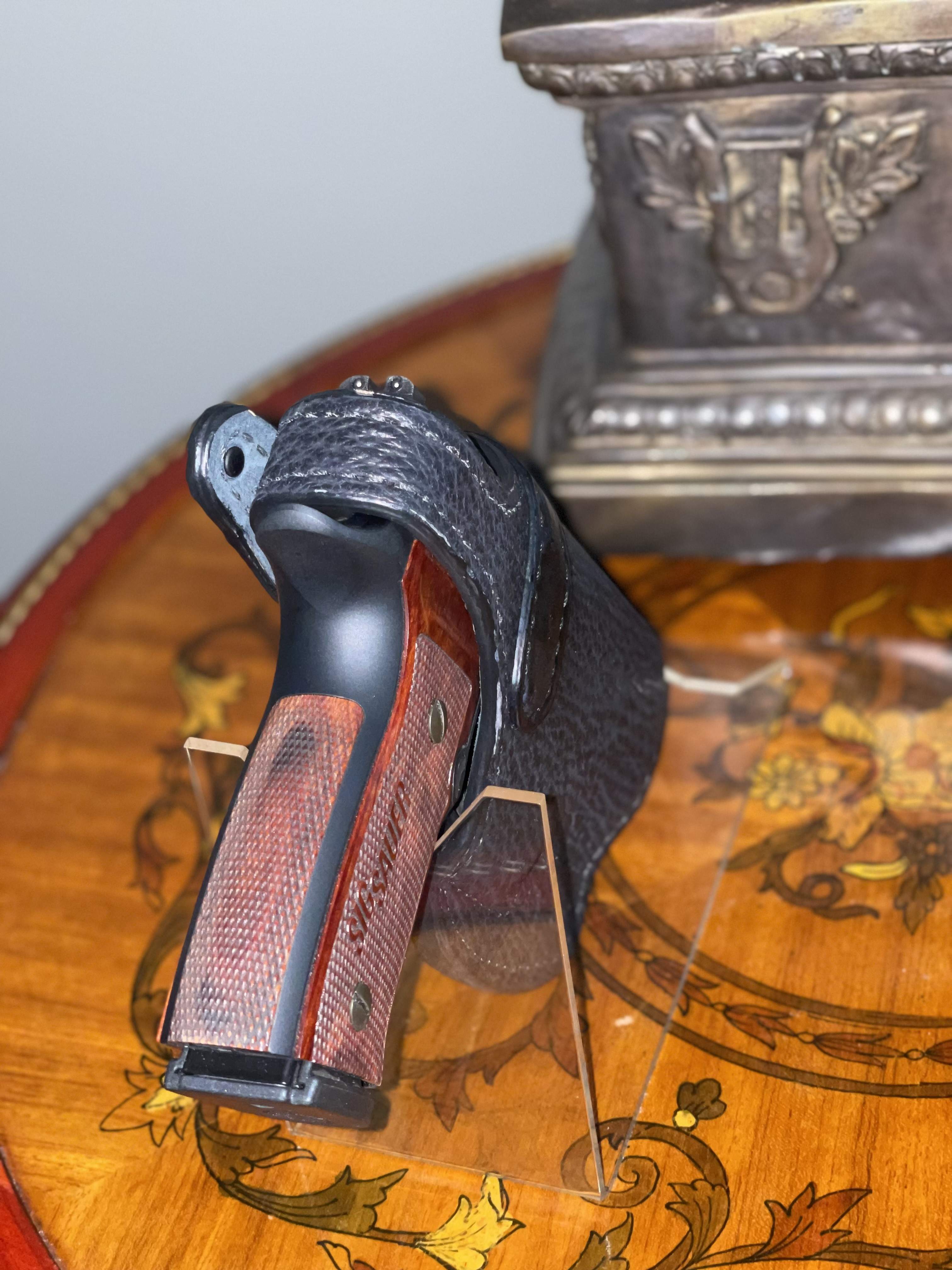 Close-up of a thumb-break paddle holster showing retention strap and finish contact areas